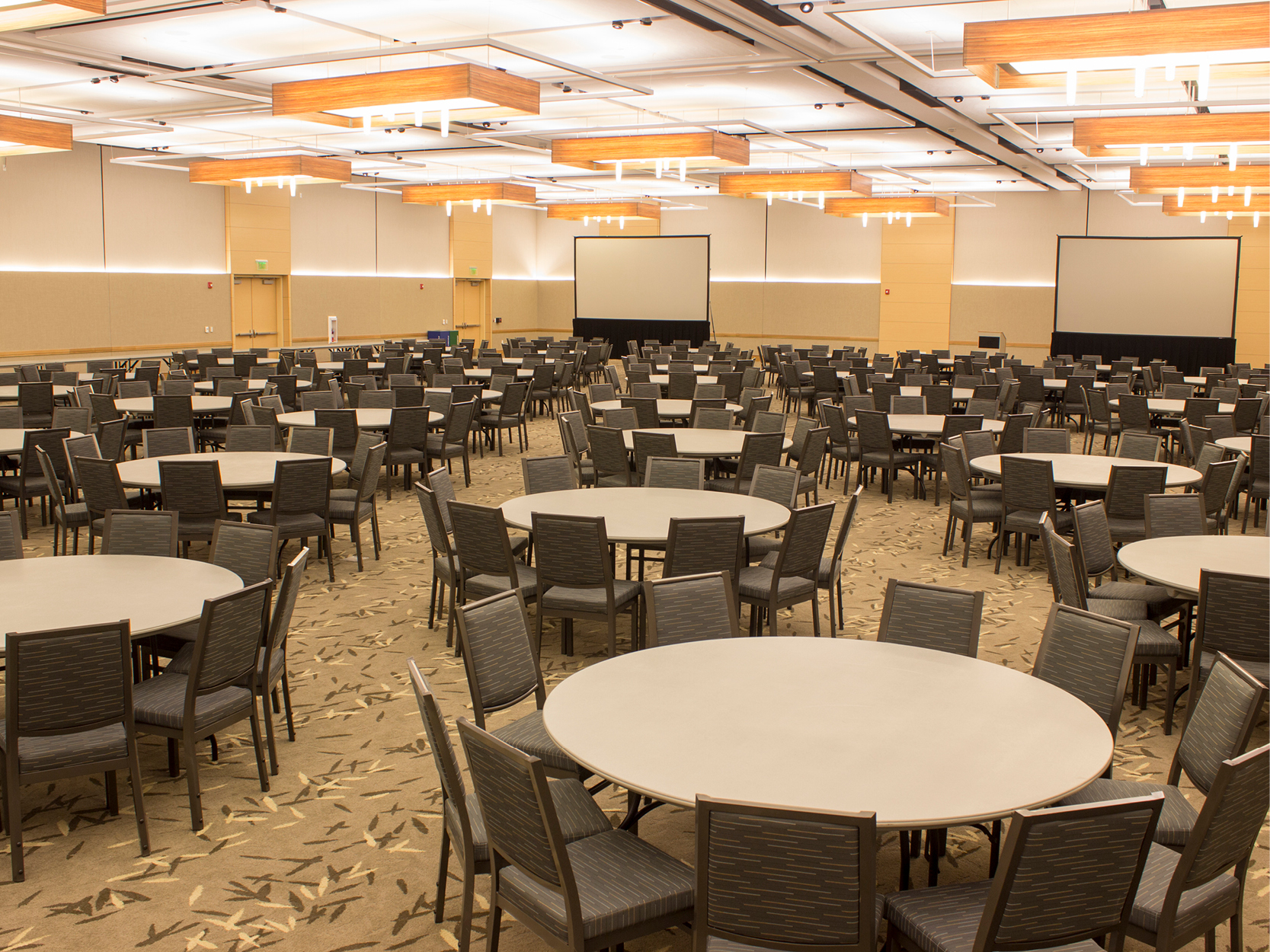 Ballroom with tables and chairs and two large screens