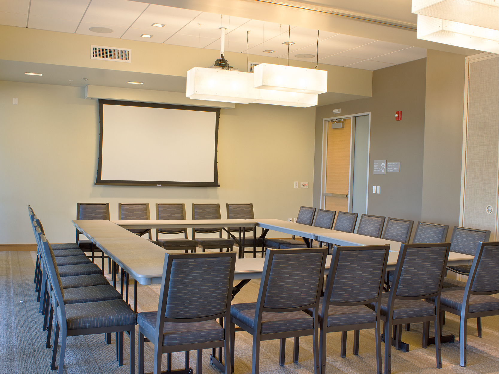 Valley room with tables and chairs and a large screen